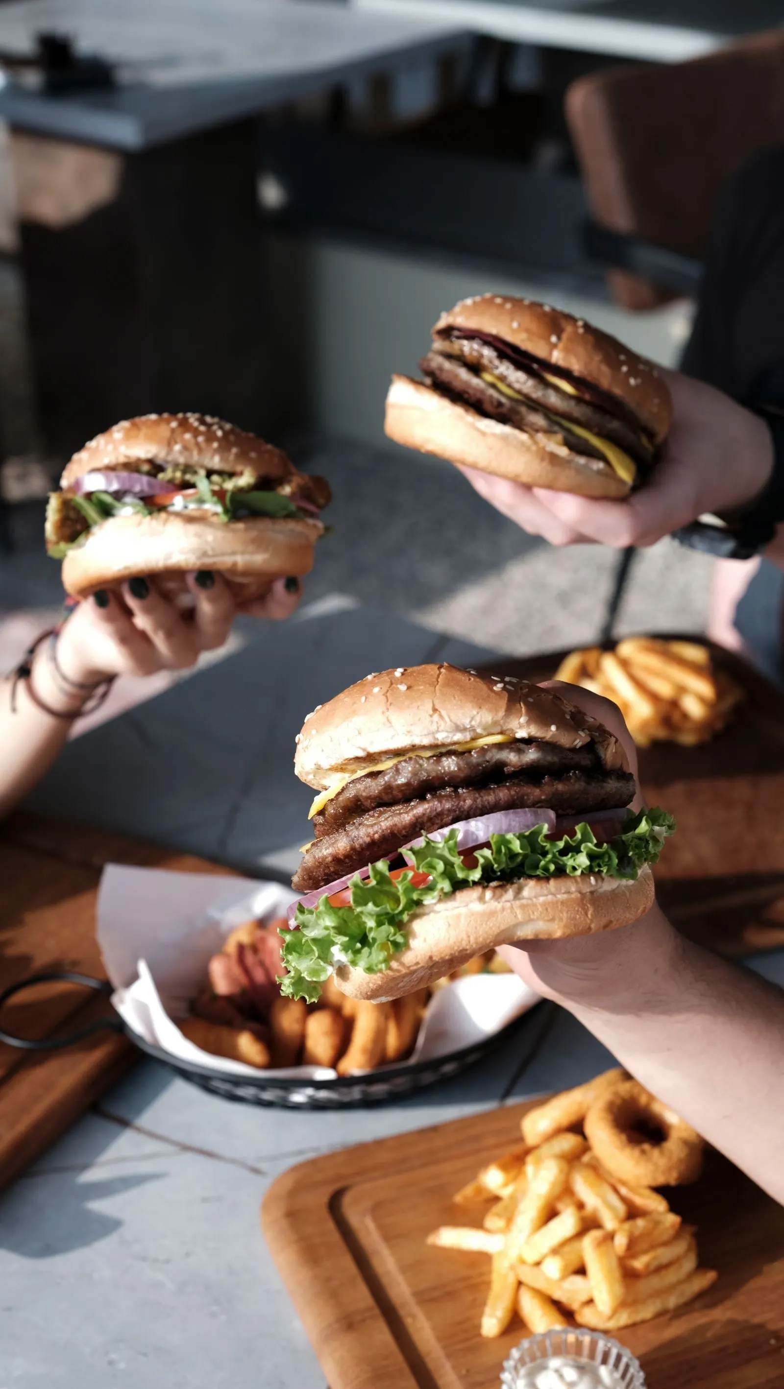 Beberapa tangan memegang burger di meja bersama
